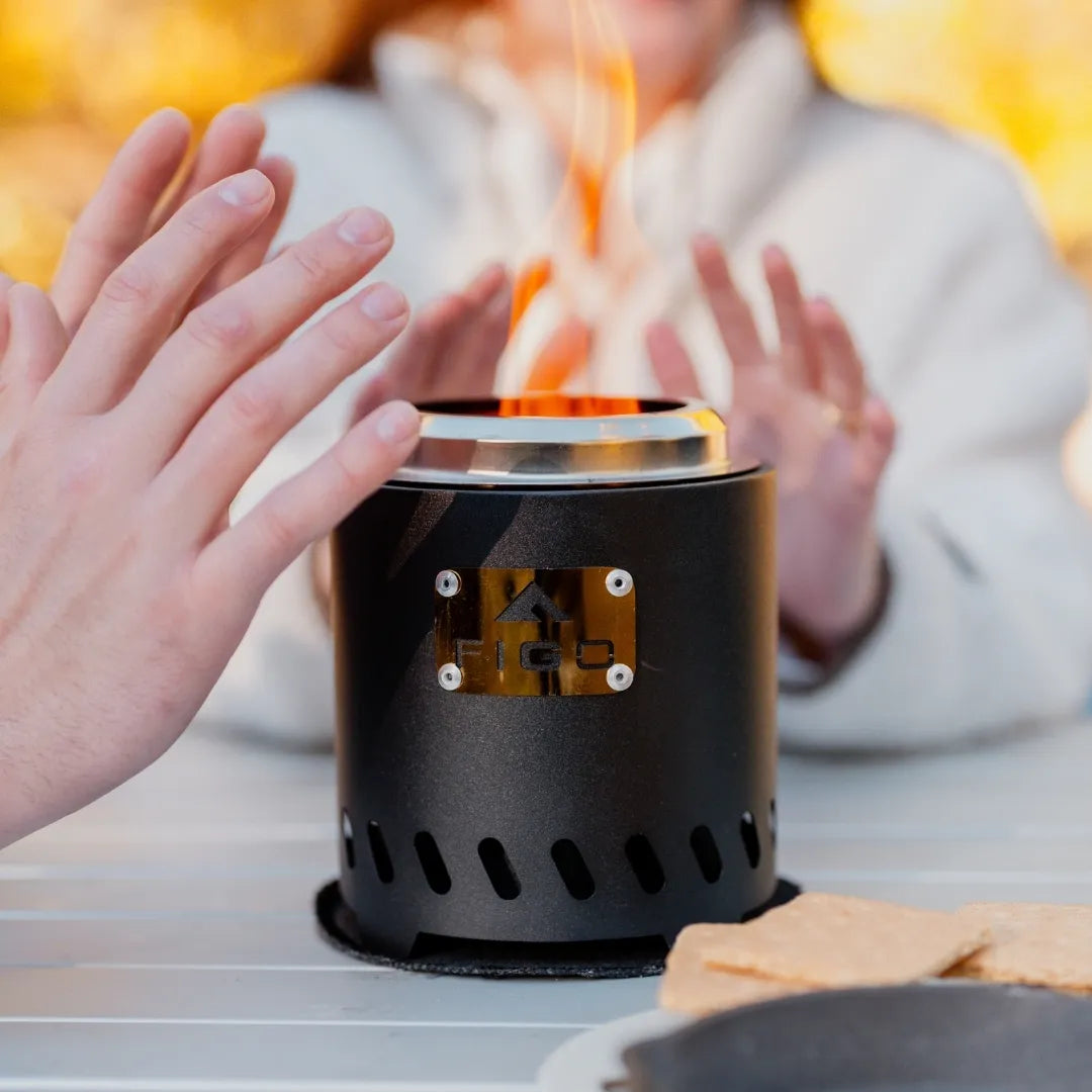 Person warming hands over a portable fire pit with flames